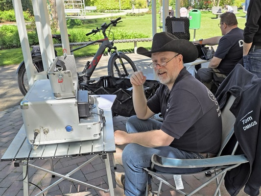 Zwei Personen im Pavillon; ein Operator sitzt an der mobilen Amateurfunkstation.